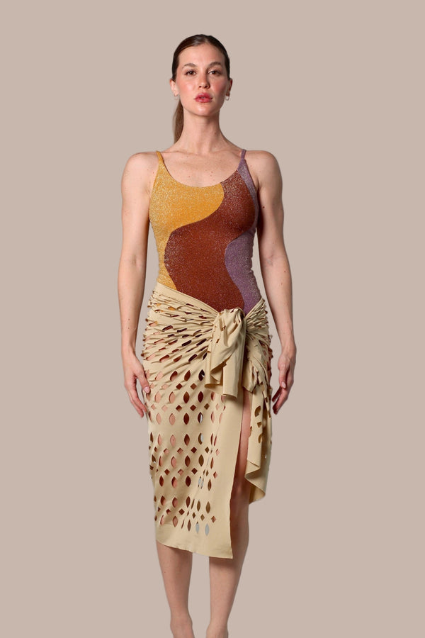 Woman wearing a sleeveless top and beige skirt with abstract patterns on a plain background